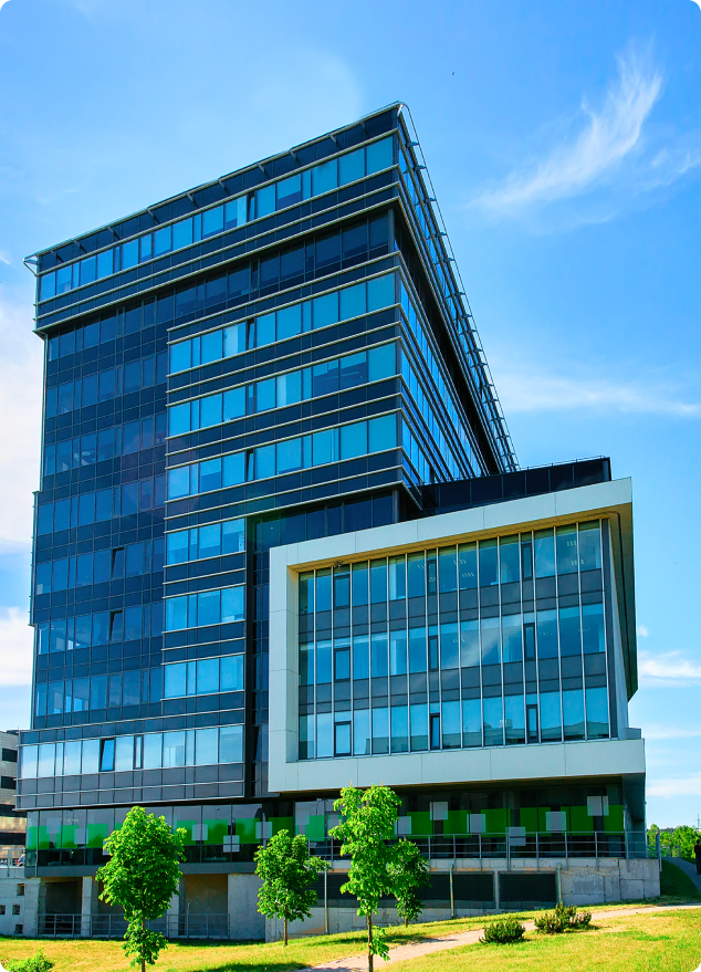 Blue glass skyscraper with green lawn.