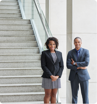 Two professionals standing confidently in front of a staircase